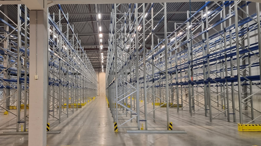 Pallereolanlegg med galvaniserte stiger og blå bærejern i en stor lagerhall.